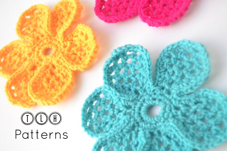 May include: Three crocheted flowers in yellow, pink, and turquoise. The flowers are all the same size and shape, and they have a simple, delicate design. The flowers are arranged in a row on a white background. The text "TLH Patterns" is below the flowers.