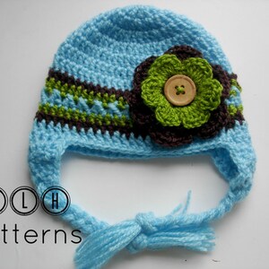 May include: A light blue crocheted hat with a brown and green stripe and a brown crocheted flower with a green center and a wooden button. The hat has a long tie that can be tied under the chin.