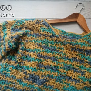 May include: A crocheted sweater in a striped pattern of mustard yellow, teal, and gray yarn. The sweater is hanging on a wooden hanger.