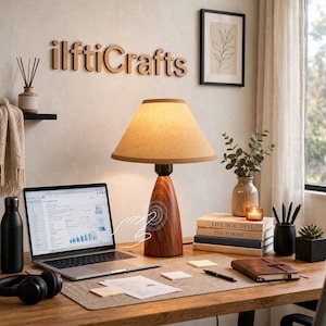 May include: A table lamp with a conical wood-grain base and a beige fabric shade. The lamp features a touch-sensitive control area on the base, indicated by a graphic overlay. It sits on a desk alongside a laptop, books, and office supplies.