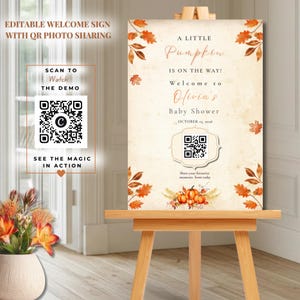 May include: A rectangular welcome sign on a wooden easel featuring autumn leaves, pumpkins, and the text A LITTLE Pumpkin IS ON THE WAY! Welcome to Olivia's Baby Shower OCTOBER 13, 2026. It includes a central QR code for photo sharing.