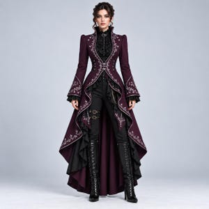 May include: A deep purple long-sleeved coat with white floral embroidery, a high collar, and a high-low hemline with black ruffled trim. The coat is worn over a black ruffled blouse, black trousers with buckled straps, and black lace-up boots.
