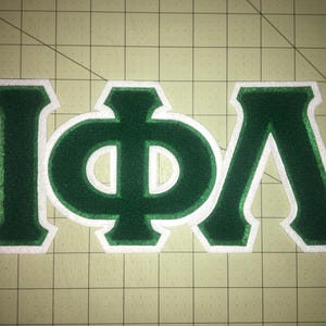 May include: Green felt letters with white outlines spelling out "IΦA".