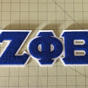 May include: Blue and white felt letter patch with the letters "ZOB".