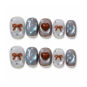 May include: A set of ten press-on nails featuring a mix of designs. Some nails are translucent with brown 3D bows and small star accents, while others are a shimmering dark gray with blue flecks or a solid brown heart center piece.