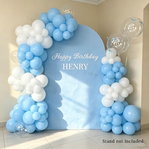May include: A light blue arched backdrop featuring the white text Happy Birthday HENRY, decorated with clusters of matte light blue and white balloons of varying sizes, along with several clear transparent balloons with blue ribbon accents.