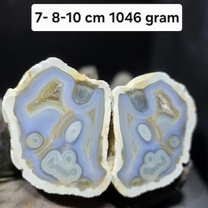 Può includere: Due metà di una geode di agata lucidata con bande concentriche in azzurro, bianco e beige. La pietra presenta intricati motivi circolari e centri cristallini. Il testo sull'immagine riporta 7- 8-10 cm 1046 gram.