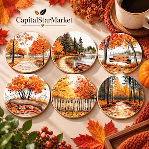 May include: A set of six round coasters featuring watercolour-style autumn landscapes. The designs include a park bench, a lakeside boat, a hanging swing, a fox resting by a log, a wooden fence, and a forest path, all with vibrant orange and red foliage.