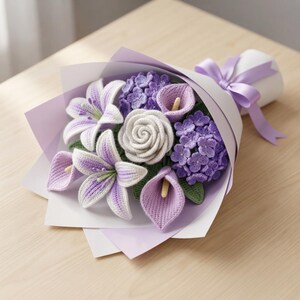 May include: A crochet flower bouquet featuring white and purple lilies, a central white rose, purple calla lilies, and clusters of small purple hydrangea blossoms. The arrangement is wrapped in light purple paper and tied with a matching ribbon.