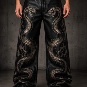 Könnte beinhalten: Schwarze Kunstlederhose mit weitem Bein und einem auffälligen Grafikdruck von zwei großen, gewundenen Schlangen in Metallic-Silber. Die Schlangen erstrecken sich von der Taille bis zum Saum und zeigen detaillierte Schuppen und sichtbare Giftzähne.