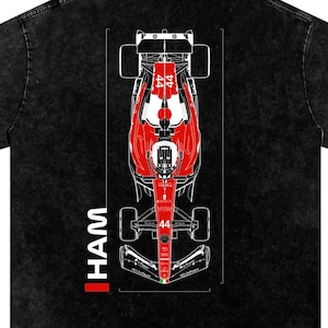May include: A black acid-wash t-shirt featuring a top-down graphic of a red and white Formula 1 race car with the number 44 on the body. The text HAM is printed vertically in white next to the car, accompanied by a small red rectangular accent.