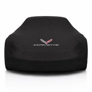Può includere: Un telo copriauto nero progettato per un veicolo, caratterizzato dal logo Corvette bianco e rosso e dalla scritta CORVETTE stampata in bianco sulla parte anteriore centrale. Il tessuto è liscio e opaco, seguendo la forma del muso dell'auto.