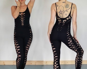 May include: Black jumpsuit with cutouts and a lace-up detail in the front. The jumpsuit is made of a stretchy fabric and has a fitted silhouette.
