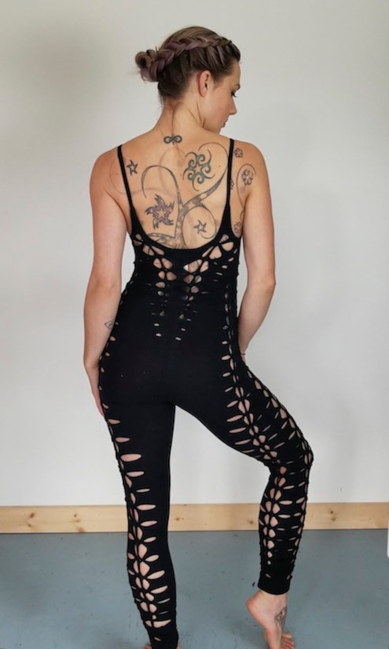 May include: Black jumpsuit with cutouts on the legs and back. The jumpsuit is made of a stretchy fabric and has a fitted silhouette.