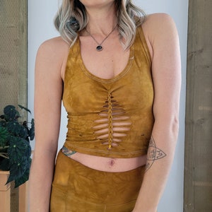 May include: A mustard yellow halter top with a braided detail and cutouts. The top is made of a soft, flowy fabric and has a relaxed fit.