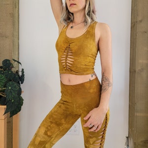 May include: A mustard yellow crop top with a lace-up detail in the front and matching mustard yellow leggings with a lace-up detail on the side.