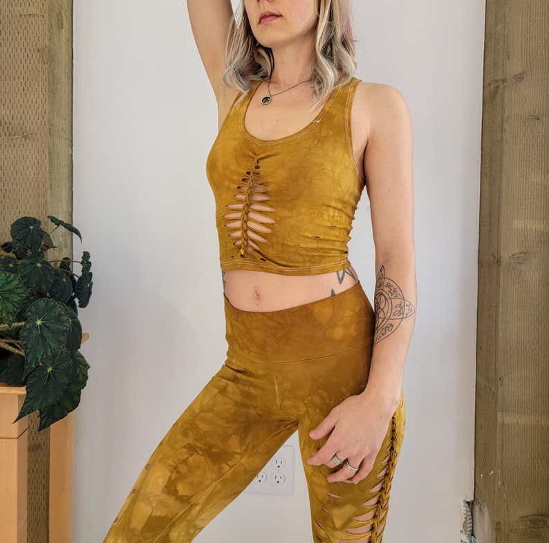 May include: A mustard yellow crop top with a lace-up detail in the front and matching mustard yellow leggings with a lace-up detail on the side.