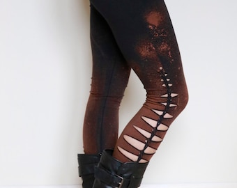 Puede incluir: Leggings negros con salpicaduras de lejía marrón y un diseño recortado en el lateral. Los leggings se combinan con botines negros.