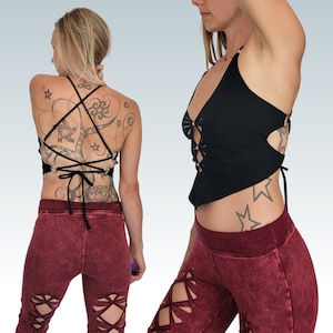 Op de afbeelding: Een zwart crop top met een veter aan de voorkant en een strik aan de achterkant. Het topje wordt gedragen met een bordeauxrode broek die veters heeft op de benen.