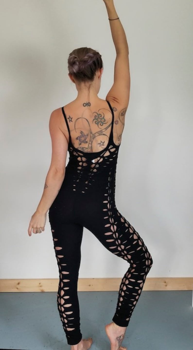 May include: Black one-piece jumpsuit with cutouts on the legs. The jumpsuit is made of a stretchy fabric and has a fitted silhouette.
