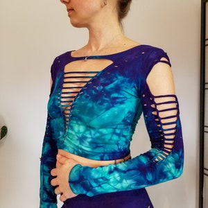 Pu&ograve; includere: Un top corto blu e verde tie-dye con maniche lunghe e tagli alle spalle e al collo. Il top &egrave; realizzato in un tessuto morbido ed elastico.