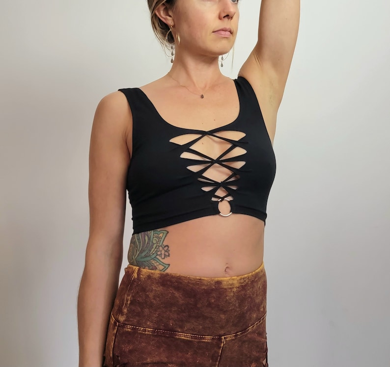 May include: A black crop top with a criss-cross lace-up design in the front. The top has a scoop neck and a relaxed fit.