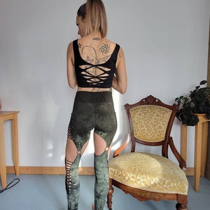 May include: Green and black leggings with cutouts and tie details. The leggings are made of a stretchy, comfortable fabric and have a tie detail at the waist.