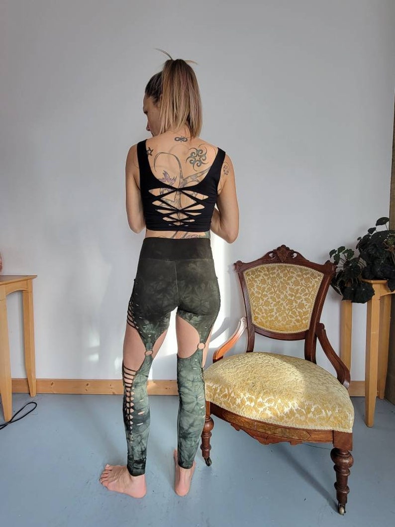 May include: Green and black leggings with cutouts and tie details. The leggings are made of a stretchy, comfortable fabric and have a tie detail at the waist.