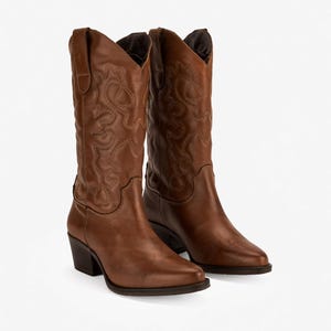 Könnte beinhalten: Ein Paar wadenhohe Cowboystiefel aus braunem Leder mit spitzer Zehenpartie, einem geschichteten Blockabsatz und dekorativen, farblich abgestimmten Ziernähten am Schaft. Die Stiefel haben Zuglaschen am oberen Rand und eine glatte Oberfläche.