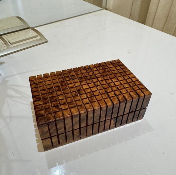 A secret-compartment puzzle box handcrafted from Thuya wood in Morocco — you have to solve it to open it, and the burl wood grain makes every one unique.