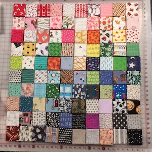 May include: A collection of 64 fabric squares with various patterns and colours, arranged in a grid pattern. The squares are all the same size and are sewn together to create a quilt block.