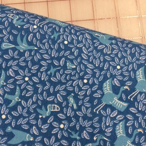May include: Blue fabric with a repeating pattern of white leaves, white dots, and blue birds. The birds are in various poses, some flying, some perched, and some with their wings spread.