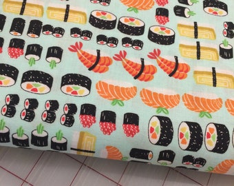 May include: A blue fabric with a repeating pattern of sushi rolls, shrimp, and seaweed. The sushi rolls are in various colors and shapes, including red, orange, yellow, and green.