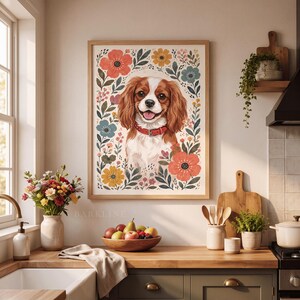 Pode incluir: Uma impress&atilde;o de arte emoldurada apresentando um spaniel Cavalier King Charles castanho e branco com uma coleira vermelha, rodeado por uma ilustra&ccedil;&atilde;o floral colorida de flores laranja, amarelas e azuis e folhas verdes num fundo creme.