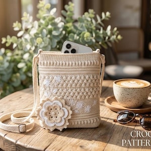May include: A beige crochet crossbody bag featuring a textured stitch pattern, a large layered floral applique, and white embroidered floral details. The bag has a long strap with a metal buckle and contains a smartphone. Text reads CROCHET PATTERN PDF.