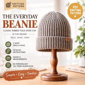 May include: A taupe ribbed knit beanie with a fold-over cuff and a small rectangular tag reading Handmade with love. The text on the image reads The Everyday Beanie, Classic Ribbed Fold-Over Cap In The Round, Skill Level: Easy, 5 Sizes, and PDF Knitting Pattern.