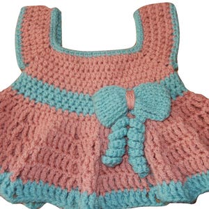K&ouml;nnte beinhalten: Ein rosa-blaues geh&auml;keltes Babykleid mit einer Schleife an der Taille.