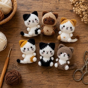Peut inclure: Six petites figurines de chats au crochet de différentes couleurs, notamment noir, blanc, marron et orange. Chaque chat a des traits du visage brodés, de petites oreilles et une queue. Un crochet en bois, des pelotes de laine et des ciseaux en métal.
