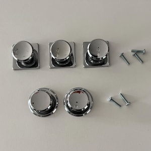 May include: Three square-based chrome cabinet knobs and two round-based chrome cabinet knobs, all featuring a polished reflective finish. The set includes four small metal mounting screws with threaded shafts, arranged alongside the hardware pieces.