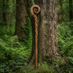 Może przedstawiać: Ręcznie rzeźbiona drewniana laska z naturalnym brązowym wykończeniem i wyraźnym spiralnym wzorem na szczycie. Trzon laski posiada ciągłą, skręconą, przypominającą linę teksturę, kt&oacute;ra biegnie pionowo wzdłuż całej długości drewna.