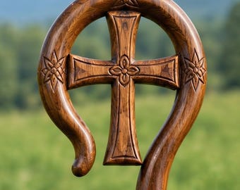 May include: A polished brown wooden crozier featuring a curved top section with carved star-like floral motifs on both sides and a central cross element with a four-petaled flower design at its intersection, showcasing a rich wood grain texture.