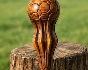May include: A hand-carved wooden walking stick handle featuring a detailed soccer ball design at the top. The wood has a polished, medium-brown finish with visible grain patterns and vertical fluted carvings extending down the shaft.
