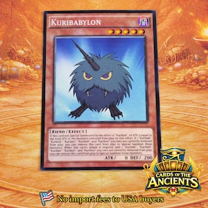 Könnte beinhalten: Eine rechteckige Sammelkarte mit dem Titel Kuribabylon, die ein dunkelblaues, stacheliges, rundes Wesen mit einem einzelnen Horn und gelben Augen zeigt. Die Karte enthält den Text Fiend/Effect, ATK/0, DEF/200 und englische Spielregeln.