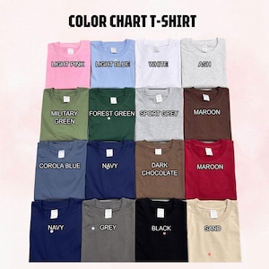 May include: A color chart t-shirt display featuring sixteen folded shirts in various shades including light pink, light blue, white, ash, military green, forest green, sport grey, maroon, corola blue, navy, dark chocolate, grey, black, and sand.