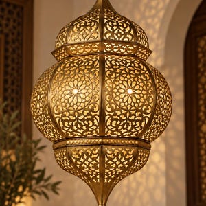May include: A hanging pendant lamp crafted from antique brass-toned metal, featuring an intricate, laser-cut geometric pattern that allows warm light to filter through. The fixture has a bulbous, multi-tiered shape with a pointed finial at the base.