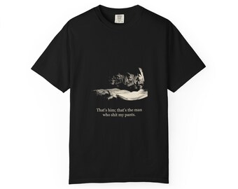 May include: A black short-sleeve t-shirt featuring a monochromatic graphic of a pointing figure and the printed text: That's him; that's the man who shit my pants. The design is centered on the chest of the garment, which has a crew neckline.