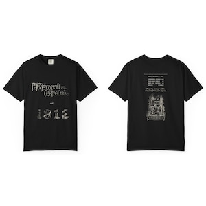 Pode incluir: Uma t-shirt preta de manga curta com texto branco desgastado na frente que diz Hansel v. Gretel est. 1812. As costas exibem uma lista de itens com preços e o texto Property damage will be deducted from your deposit.