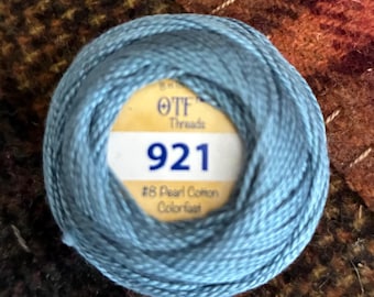 May include: A ball of light blue pearl cotton thread with a central label reading OTF Threads 921 #8 Pearl Cotton Colorfast. The thread is wound into a round shape, showcasing a smooth, twisted texture typical of embroidery or craft supplies.