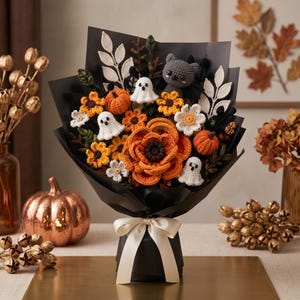 May include: A crochet bouquet featuring orange and yellow flowers, small pumpkins, white ghosts, and a grey bat, all wrapped in black paper with a cream ribbon. The arrangement includes white leaf accents and dark green foliage elements.