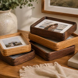 May include: A stack of four square wooden photo frames with rounded corners. Two frames are crafted from dark brown wood, and two are crafted from light tan wood. Each frame contains a white mat and a photograph, displaying images of people.